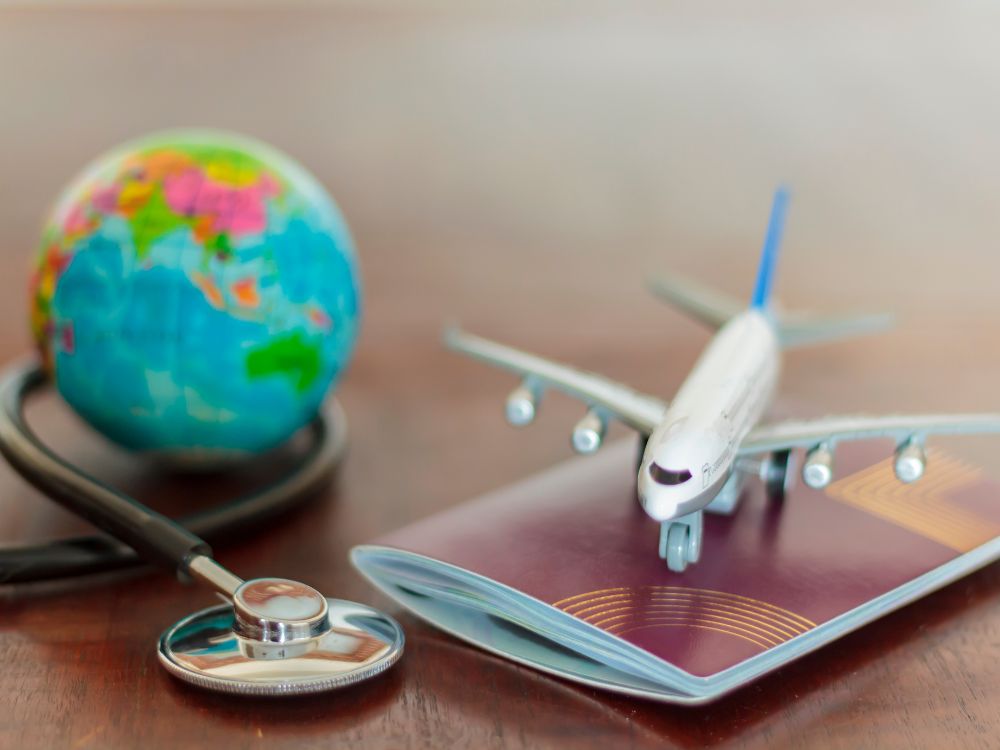  passaporte, globo,  estetoscópio e  avião sobre uma mesa
