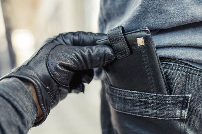 Batedor de carteira furtando uma carteira de bolso traseiro da calça de um homem.