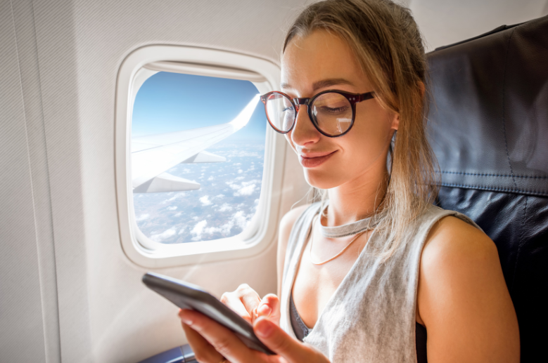mulher olhando celular com óculos de grau para mais conforto no voo