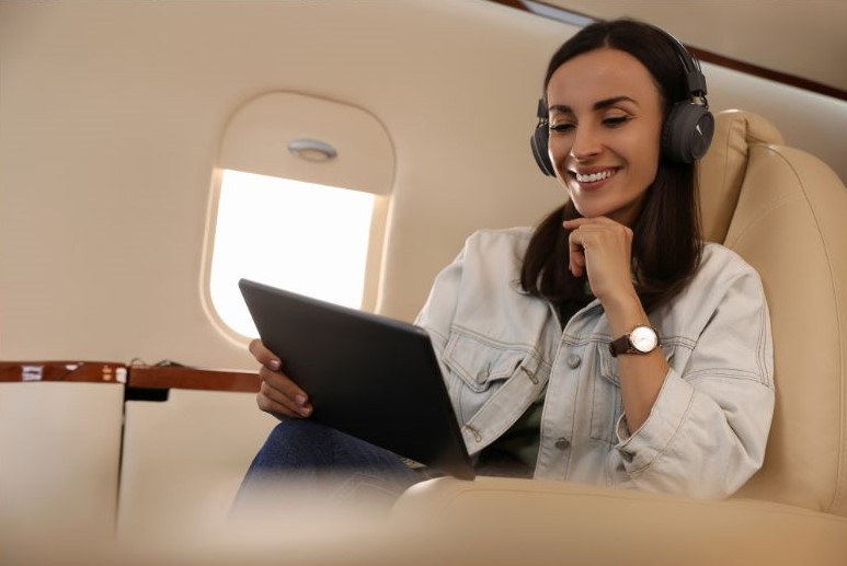 Mulher sorrindo em postura agradável durante voo olhando para o tablet
