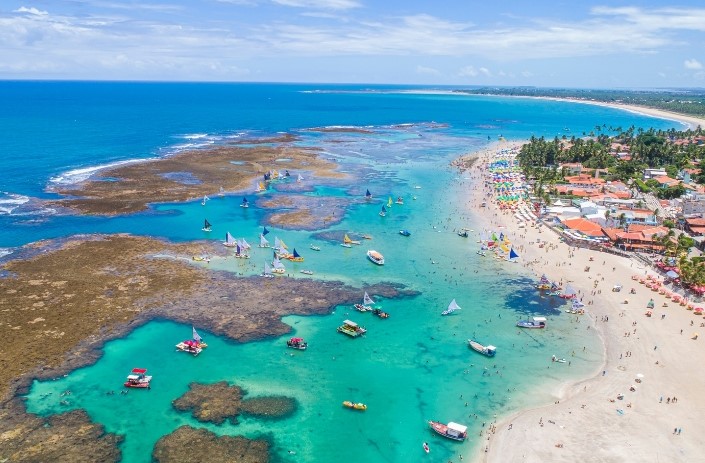 Vista aérea das piscinas naturais de Porto de Galinhas com jangadas coloridas no mar